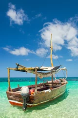 Muurstickers boat for walking in emerald sea under blue sky with clouds on Zanzibar island © sergejson