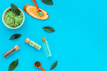 Natural organic cosmetics with tea tree essential oil near fresh tea tree leaves on blue background top view space for text border