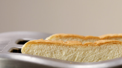 Two roasted toast bread popping up from toaster machine while smoke comes out.