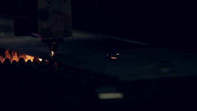 Modern programmed robot head cuts metal with sparks.