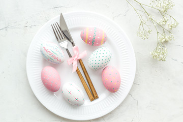 Easter table setting. Tableware and painted eggs on white background top view