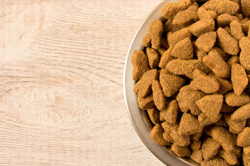 Bowl with dog food on a wooden table. Close up.