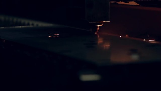 Modern programmed robot head cuts metal with sparks.