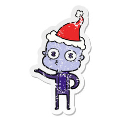 distressed sticker cartoon of a weird bald spaceman wearing santa hat