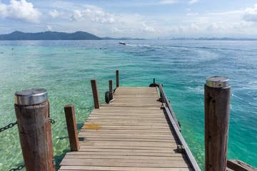 Fotobehang Beautiful wooden jetty with clear blue sky and clear blue sea water © alenthien