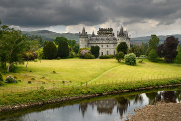 Fototapeta na wymiar Inveraray Castle reflected in the River Aray at Loch Fyne with dark clouds and golden grass in the Scottish Highlands Scotland UK