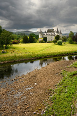 Inveraray Castle in sun reflected in the River Aray at Loch Fyne with dark clouds and sunshine in the Scottish Highlands Scotland UK