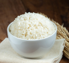 Steam White rice in white ceramic bowl on wood table for healthy meal.