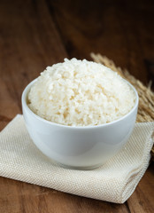 Steam White rice in white ceramic bowl on wood table for healthy meal.