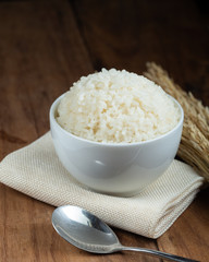 Steam White rice in white ceramic bowl on wood table for healthy meal.