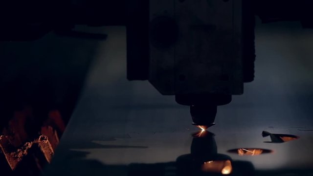 Modern programmed robot head cuts metal with sparks.