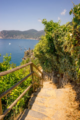 Fototapeta na wymiar Italy, Cinque Terre, Corniglia, a wooden bench sitting next to a body of water