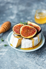Fototapeta na wymiar Camembert or brie cheese with figs, honey over blue concete background. Selective focus