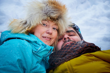 Happy loving couple in snowy winter forest. Ordinary Russian girl and handsome turkish man having fun and hug