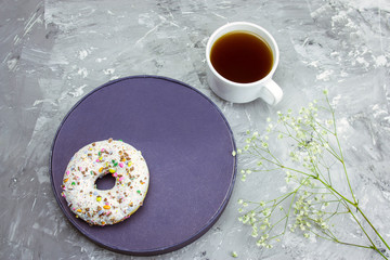 Obraz na płótnie Canvas top view cofee mug, donut on a plat and flowers on a conrete background