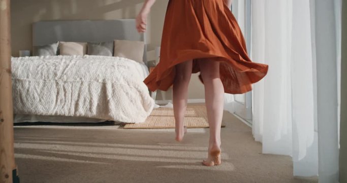 happy woman jumping on bed in hotel room having fun successful lifestyle celebrating enjoying luxury penthouse apartment