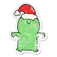 distressed sticker of a cute cartoon frog wearing christmas hat