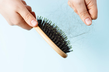 comb with loose hair on a blue background in female hand