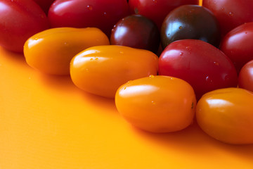 Small multicolored tomatoes on an orange background