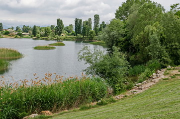 Spring panorama of a part of residential district neighborhood along a lake with green trees, shrubs and flowers, Drujba, Sofia, Bulgaria