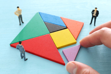 tangram puzzle blocks with miniature people over wooden table ,human resources, problem solving and...