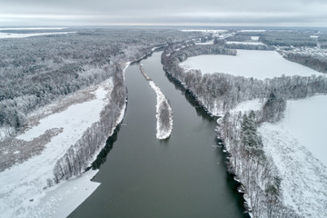 Winter landscape with a river flowing through the winter forest.