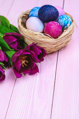Easter eggs in a nest and tulips on wooden planks