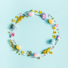 Easter eggs, purple and yellow flowers on pastel blue background. Spring, easter concept. Flat lay, top view, copy space, square