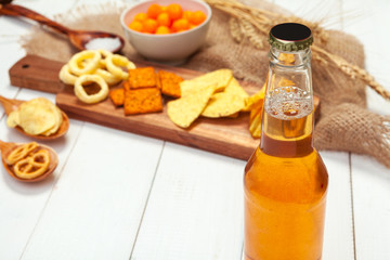 Lager beer and snacks on wooden table.