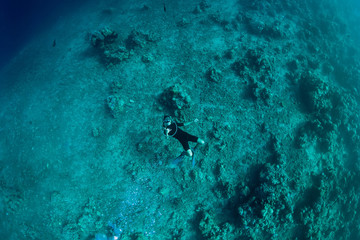 Professional freediver in wetsuit make bubbles in the ocean