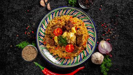 The concept of oriental cuisine. National Uzbek pilaf with meat in a cast-iron skillet, on a wooden table. background image. top view, copy space, flat lay