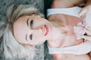 Obraz na płótnie Canvas Blonde girl is lying on the grey background