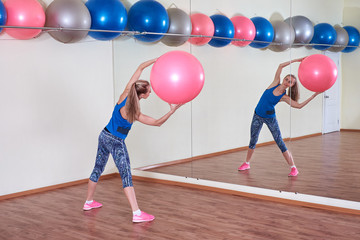 Fototapeta na wymiar Athletic woman makes exercises on a fitness ball , indoors gym.