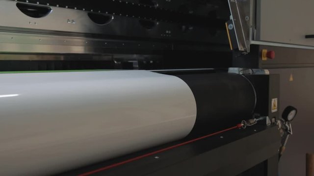 Details of a moving print head. Massive machinery. Professional  printing facility, big vinyl rolls, ready for export. Glossy, matte, ecological materials used for commercial billboards and press.