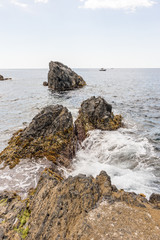 Fototapeta na wymiar Italy, Cinque Terre, Manarola, a person sitting on a rock next to a body of water