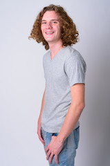 Profile view of young happy man with curly hair looking at camera