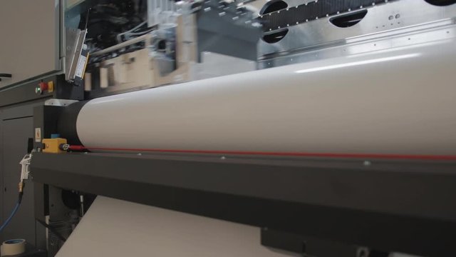 Details of a moving print head. Massive machinery. Professional  printing facility, big vinyl rolls, ready for export. Glossy, matte, ecological materials used for commercial billboards and press.