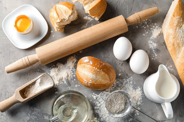 Fototapeta na wymiar Bakery products with rolling pin and ingredients for dough on grey background