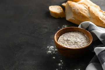 Fototapeta na wymiar Bowl of flour with French bread on grey background
