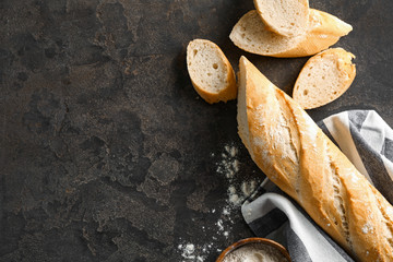 Cut French bread with flour on grey background