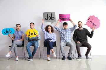 Young people holding speech bubbles with words JOB and CAREER indoors