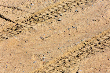 Traces of tire treads on a dry soil surface.