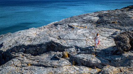 the woman walks on the rocky seashore.