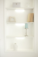  Light classic living room interior. White closet with shelves and items on them
