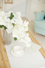 Fototapeta na wymiar Light classic living room interior. coffee table and white orchid in vaz. A bright sunny day