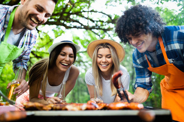 Group of happy friends eating and drinking beers at barbecue dinner