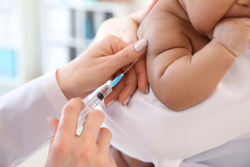 Obraz na płótnie Canvas Pediatrician giving little baby an injection in clinic