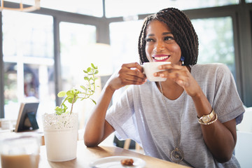 Beautiful young african woman enjoying a cup of coffee while relaxing at coffee shop