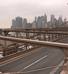 Fototapeta na wymiar Brooklyn bridge with Manhattan skyline under gray cloudy sky in background