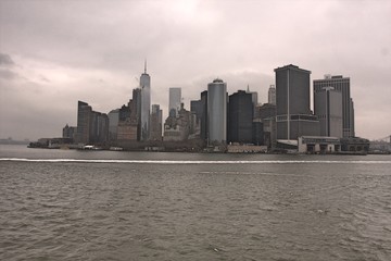 Manhattan skyline with river in foreground on cloudy, rainy day with gray sky